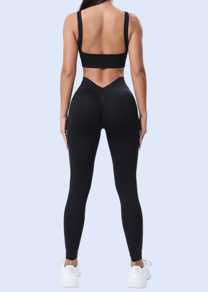 Person wearing black athletic leggings and sports bra on a light purple background