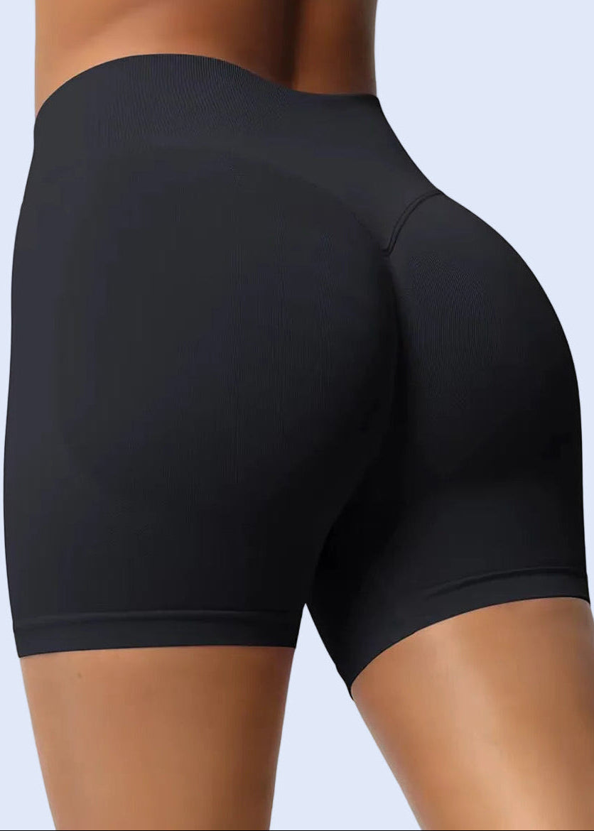 Black athletic shorts worn by a person on a plain background