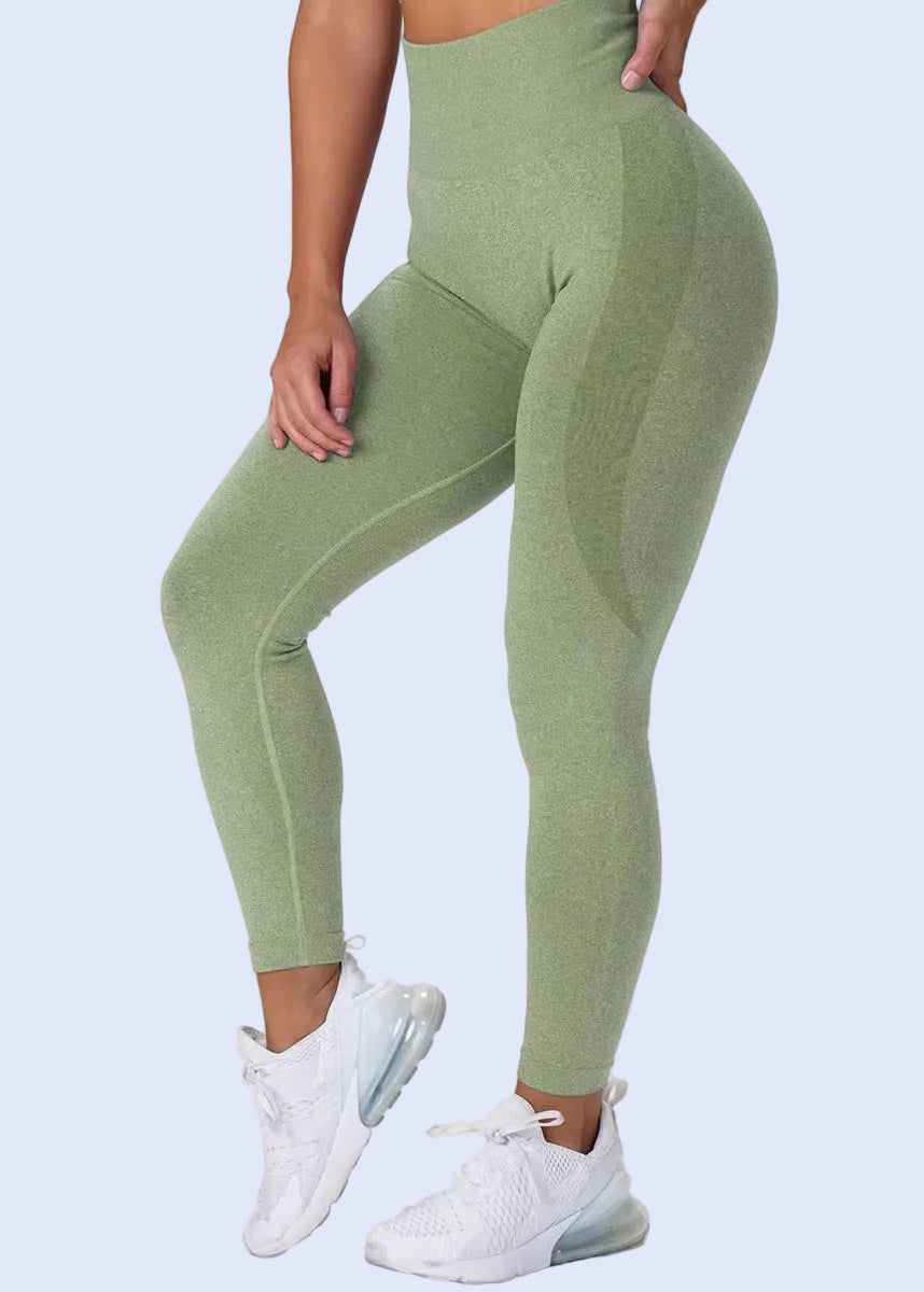 Person wearing green leggings and white sneakers on a plain background