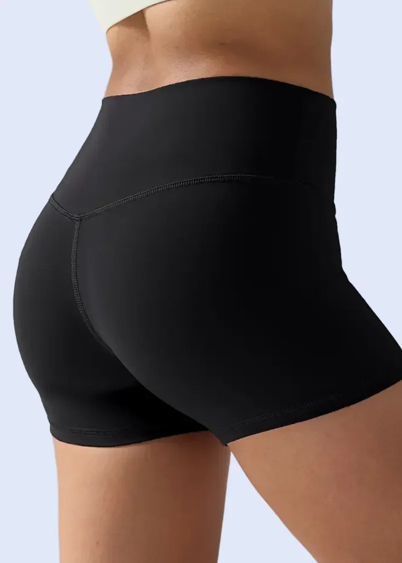 Black athletic shorts worn by a person on a plain background