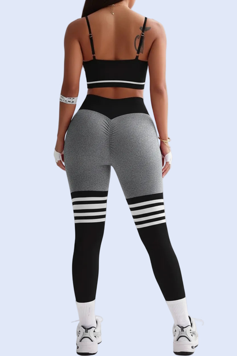 Person wearing a black sports bra and gray leggings with white stripes on a white background