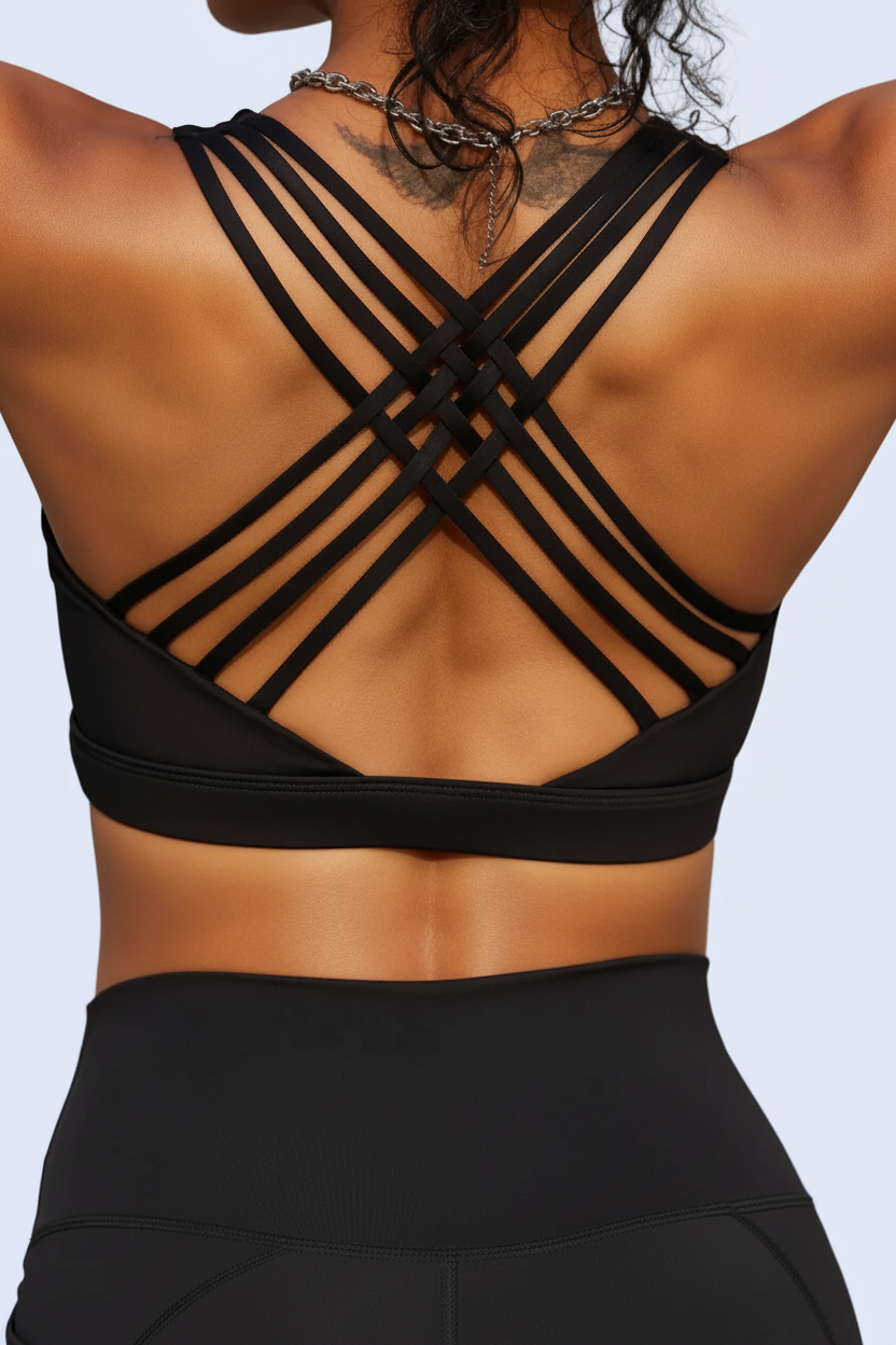 Person wearing a black sports bra and leggings with criss-cross straps on a neutral background