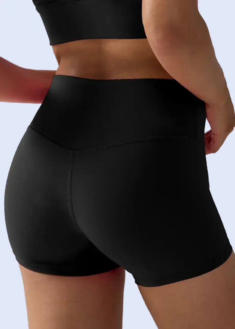 Black athletic shorts worn by a person on a plain background