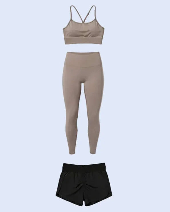 Set of beige sports bra and leggings with black shorts on a white background