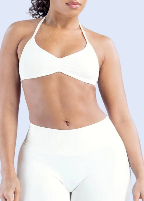Person wearing a white sports bra and leggings on a light gray background