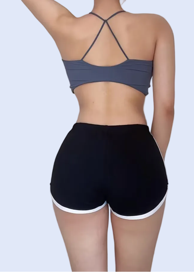 Woman wearing a blue sports bra and black shorts on a white background