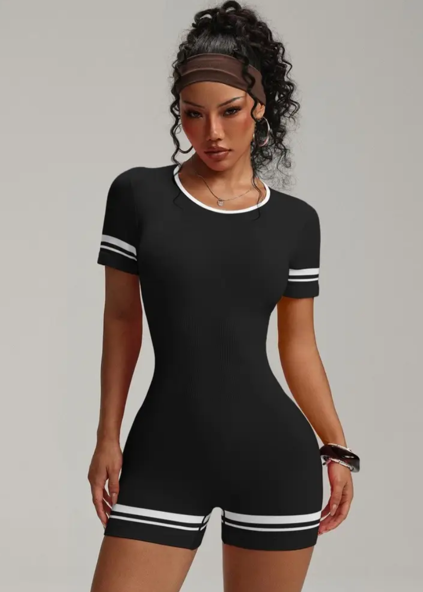 Woman wearing a black outfit with white stripes on a gray background