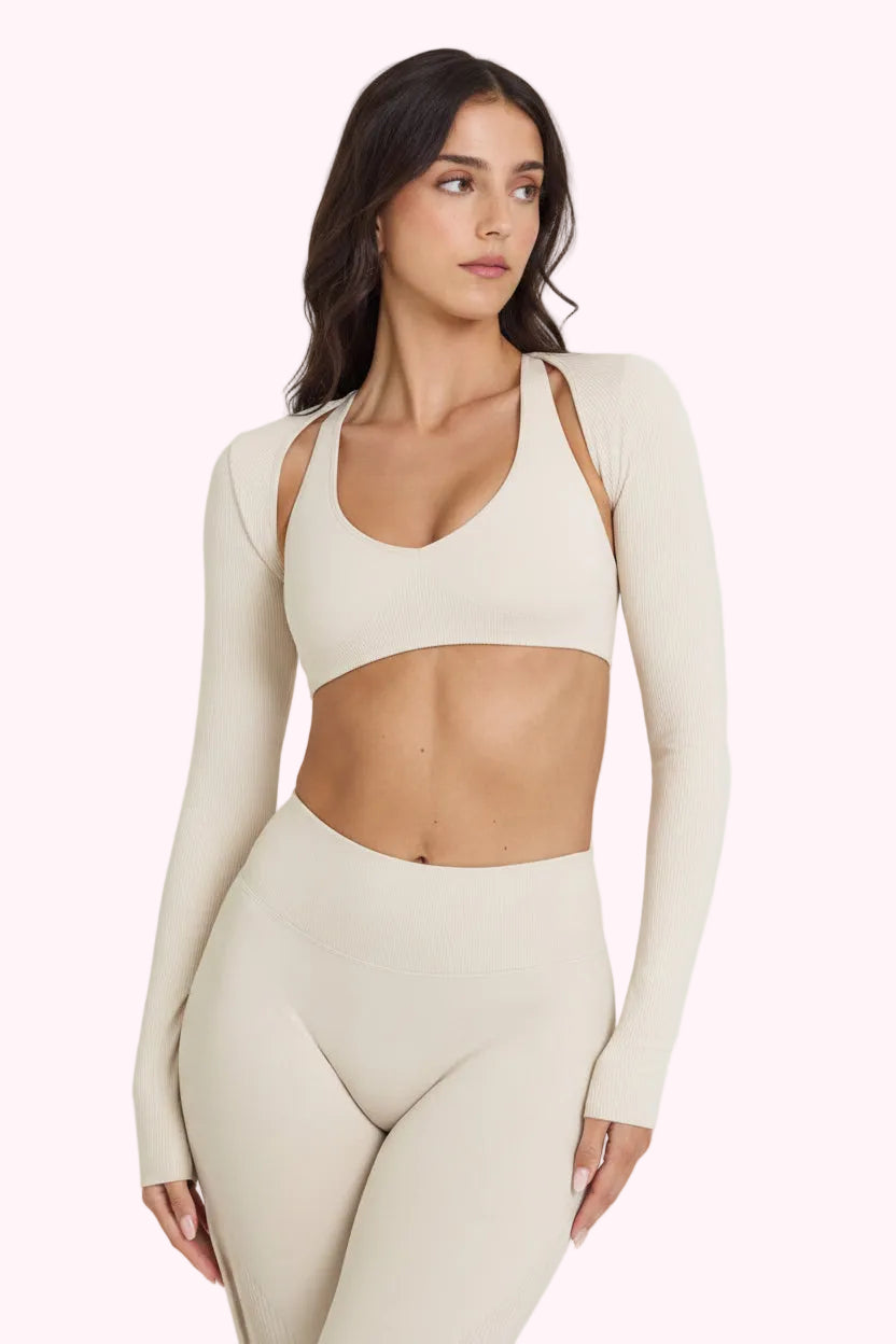 Woman wearing a beige long-sleeve athletic top and leggings on a white background