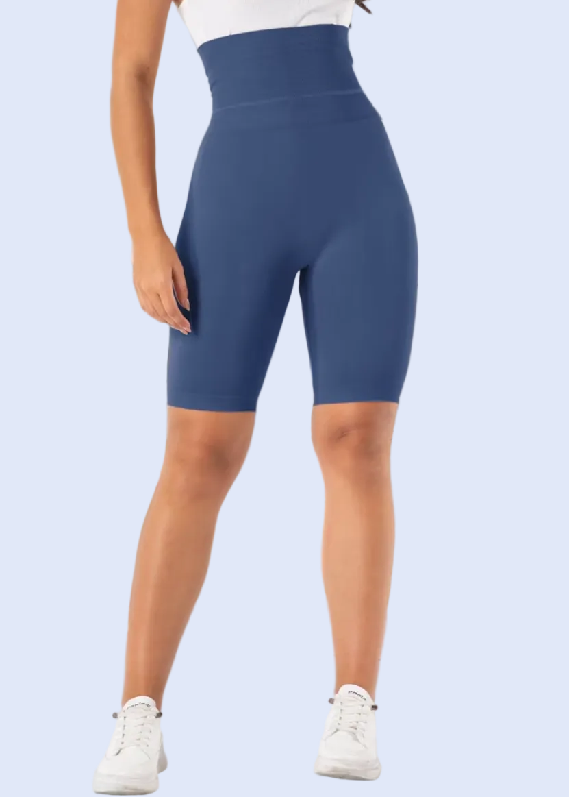 Person wearing blue high-waisted shorts in a room with a window and plant.