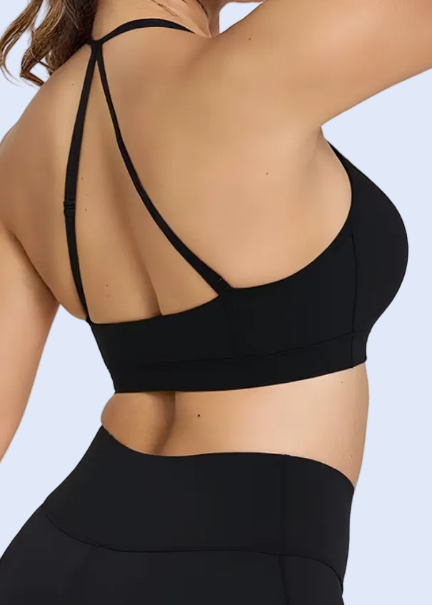 Woman wearing a black sports bra and leggings on a plain background