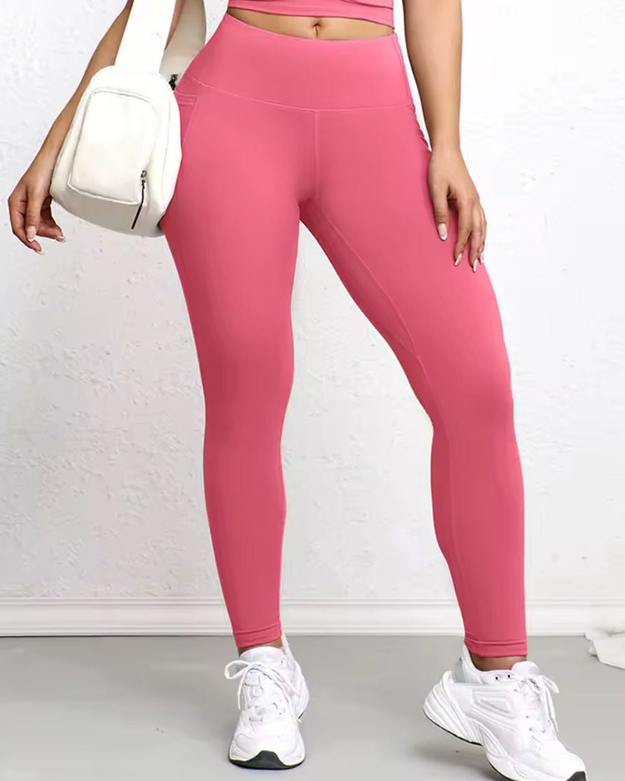 Person wearing pink leggings and white sneakers on a plain background