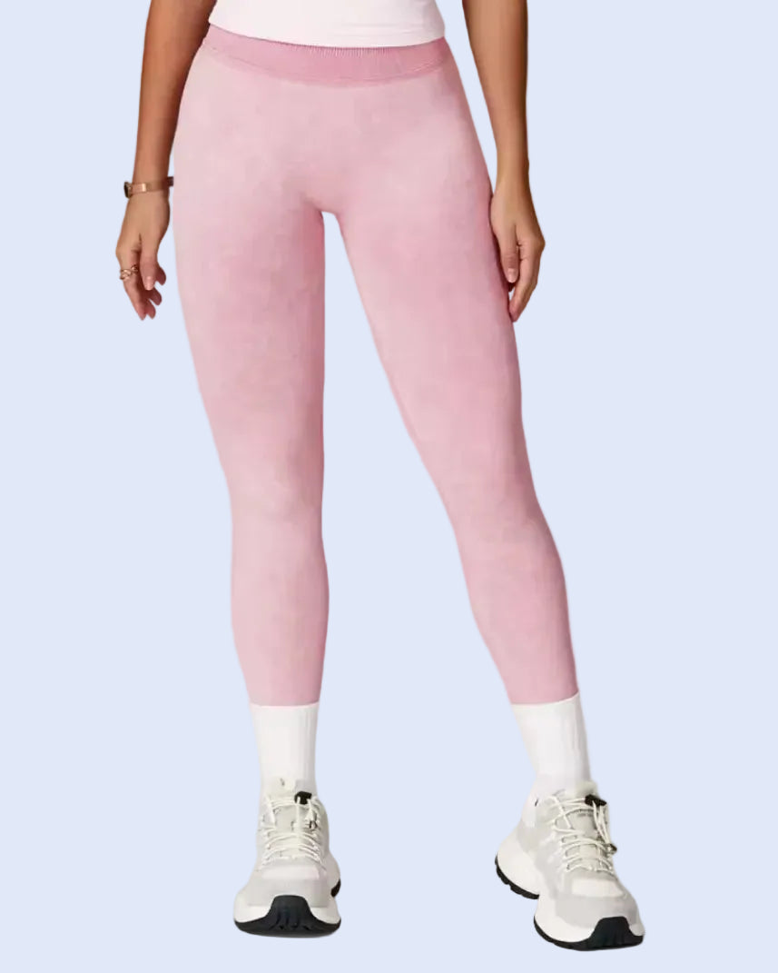 A model wearing light pink athletic leggings, white crew socks, and white sneakers, shown from the waist down against a light gray studio background.