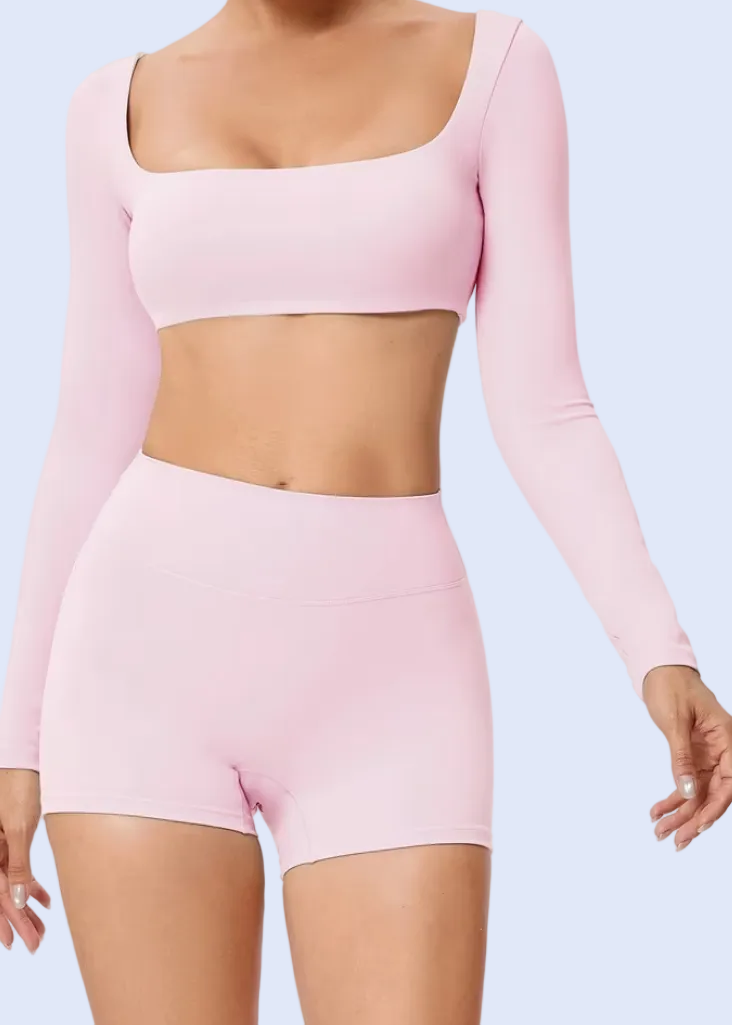 Person wearing a pink long-sleeve crop top and shorts on a white background