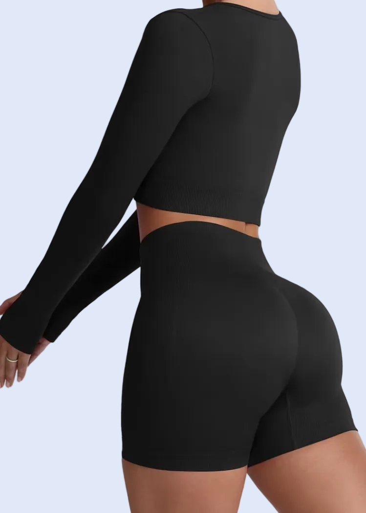 Person wearing a black long-sleeve top and shorts on a white background