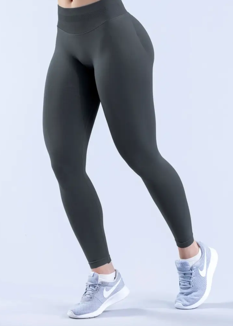 Person wearing black leggings and white sneakers on a light gray background