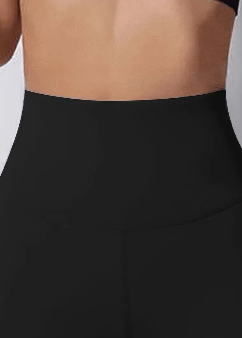 Black high-waisted pants worn by a person on a light gray background