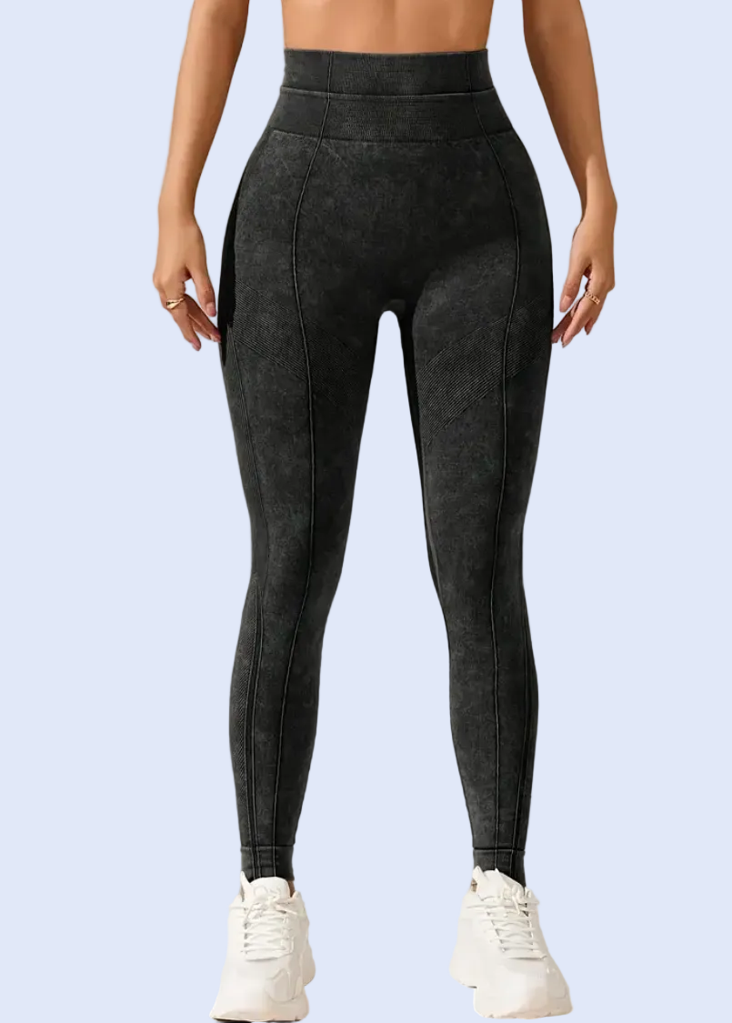 Person wearing dark gray leggings on a plain background