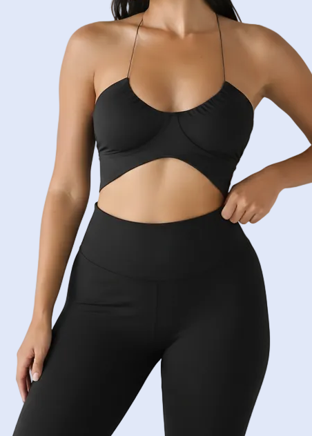 Woman wearing a black strappy top against a plain background