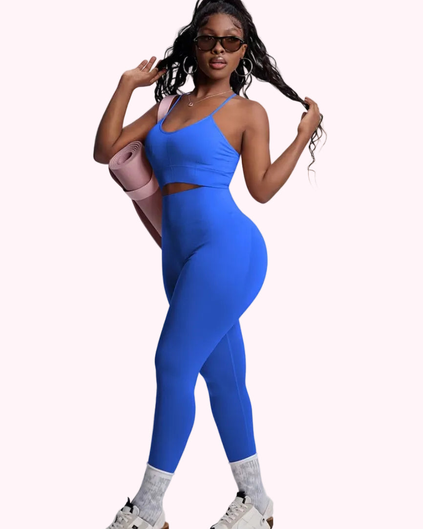 Woman in blue athletic outfit holding a pink yoga mat on a white background