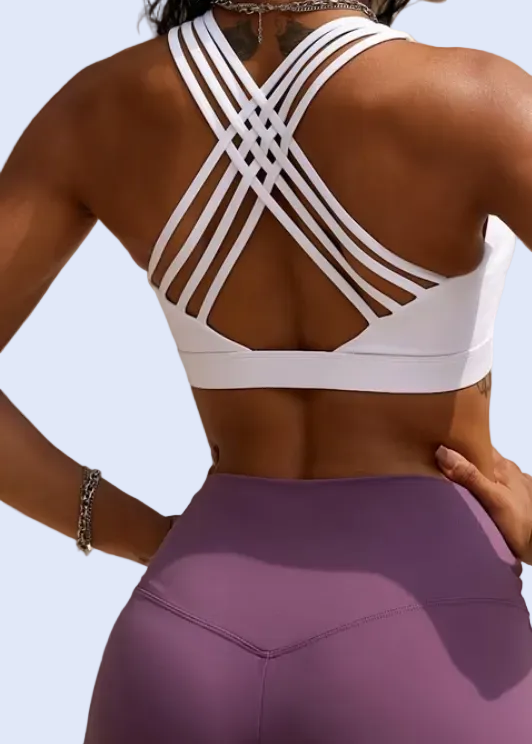 Woman wearing a white sports bra and purple leggings with a blurred background