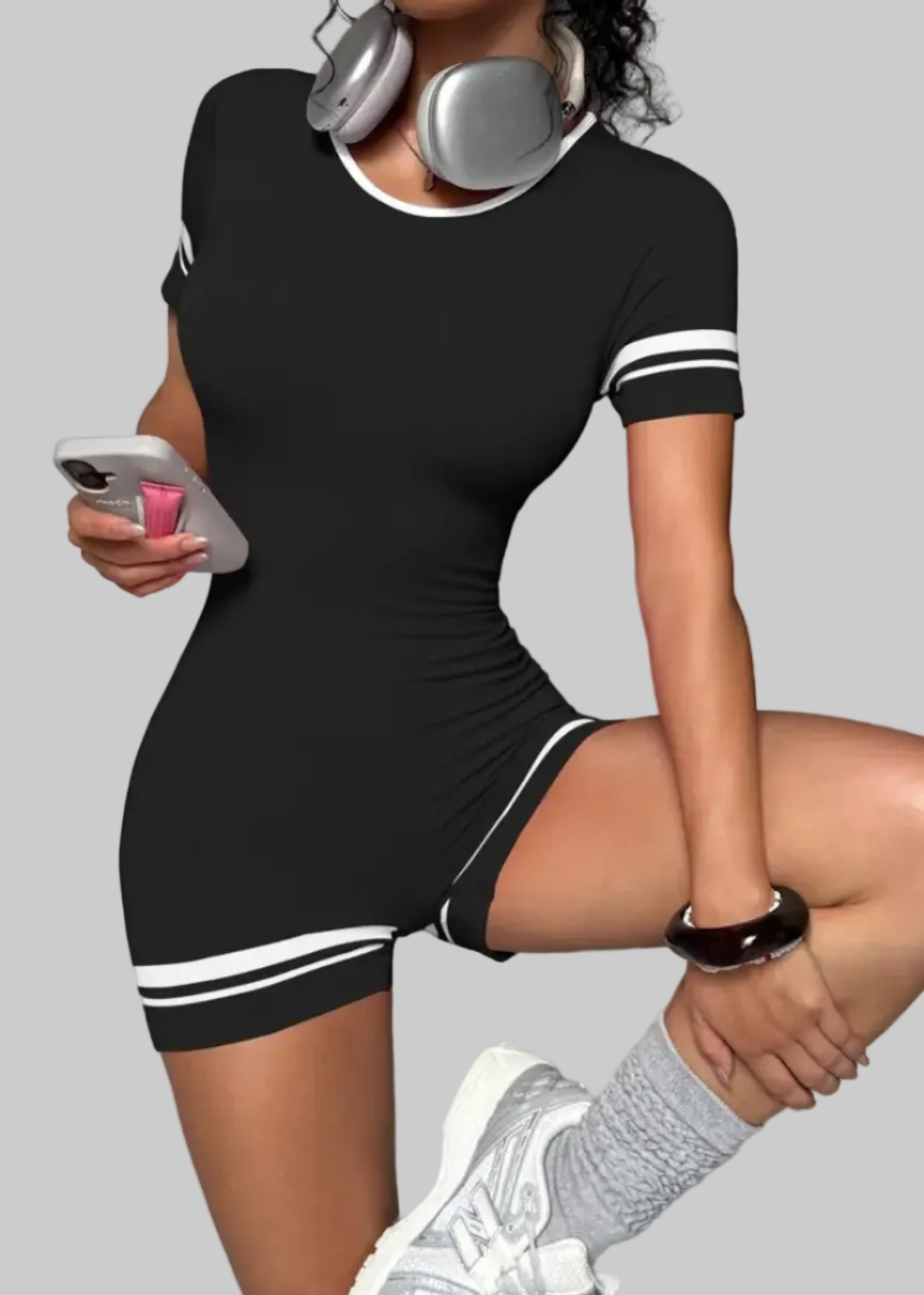 Woman in a black dress with white stripes holding a phone on a gray background