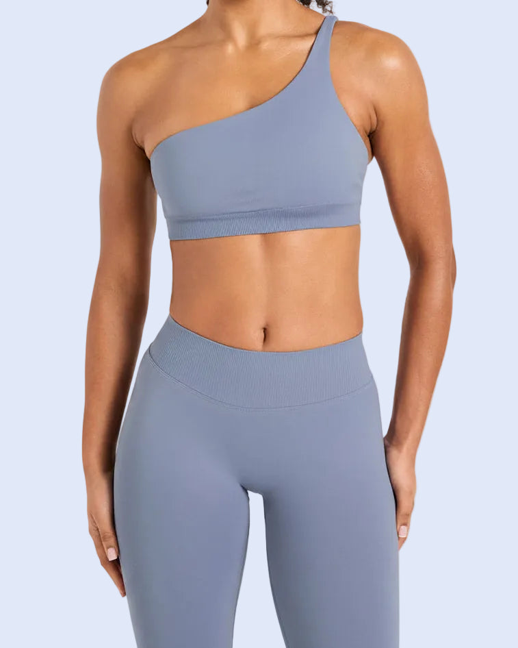 Person wearing a blue sports bra and leggings on a light gray background