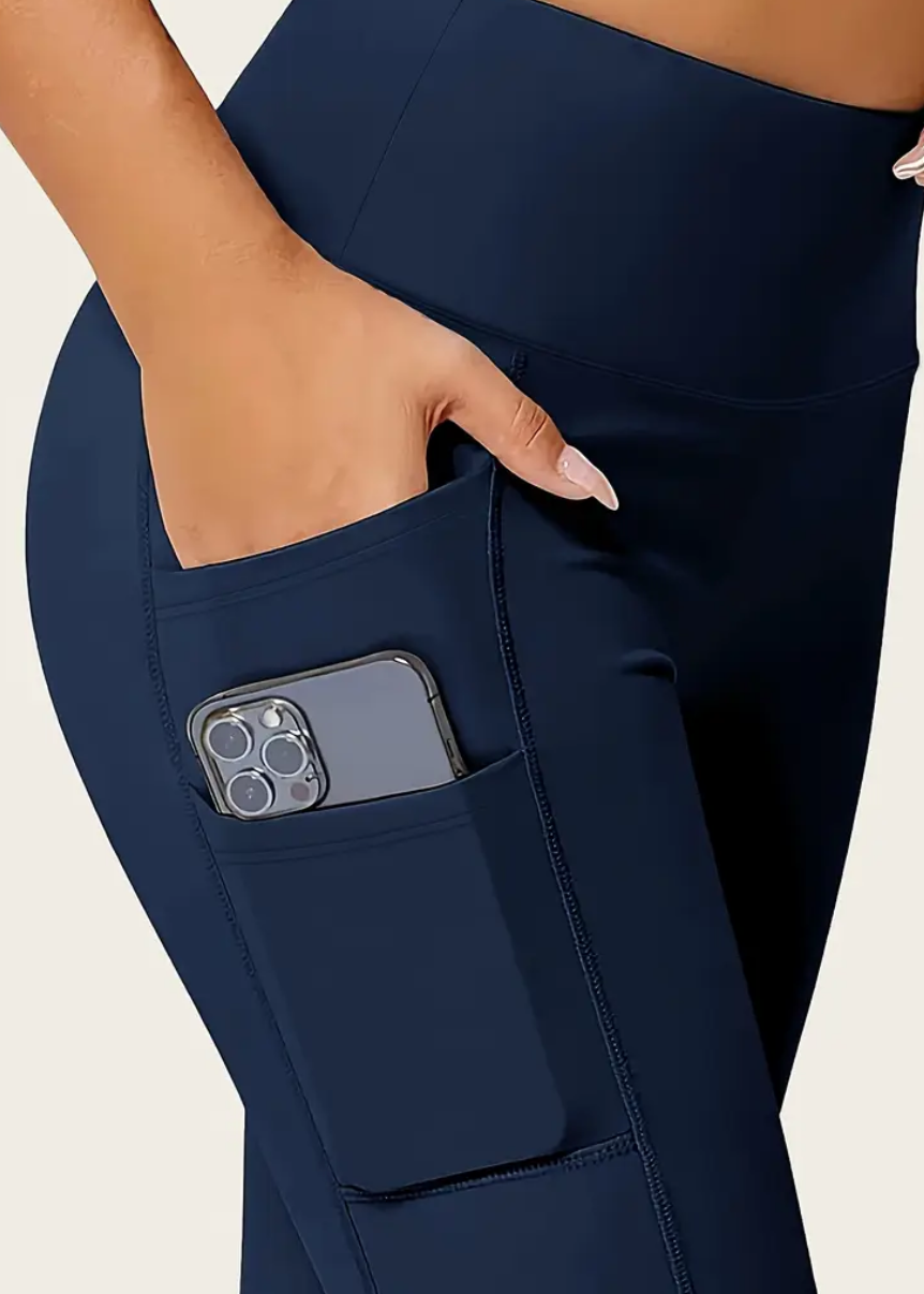 Navy blue pants with a pocket holding a phone on a light gray background