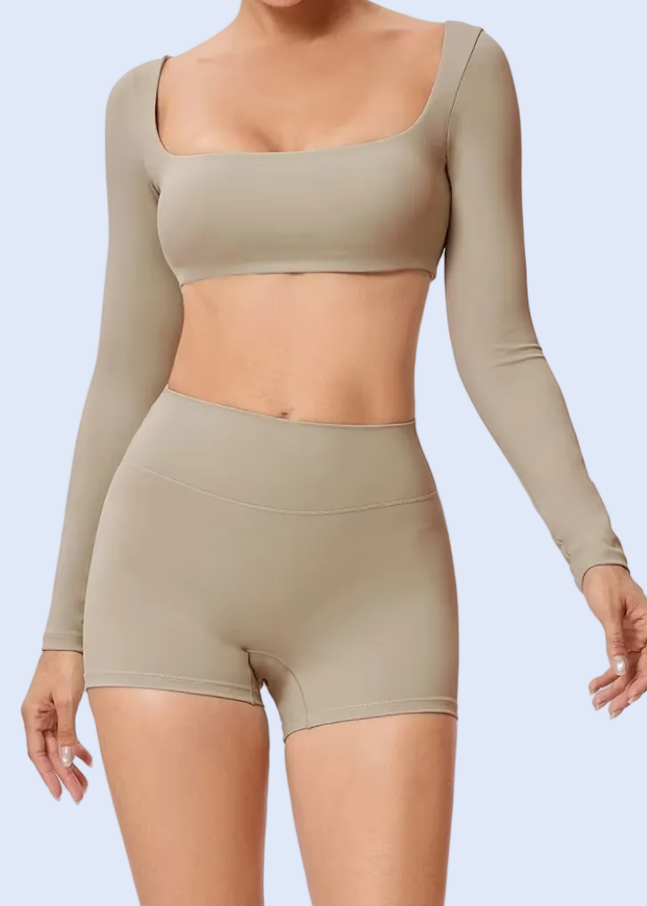 Person wearing a beige long-sleeve top and shorts on a white background