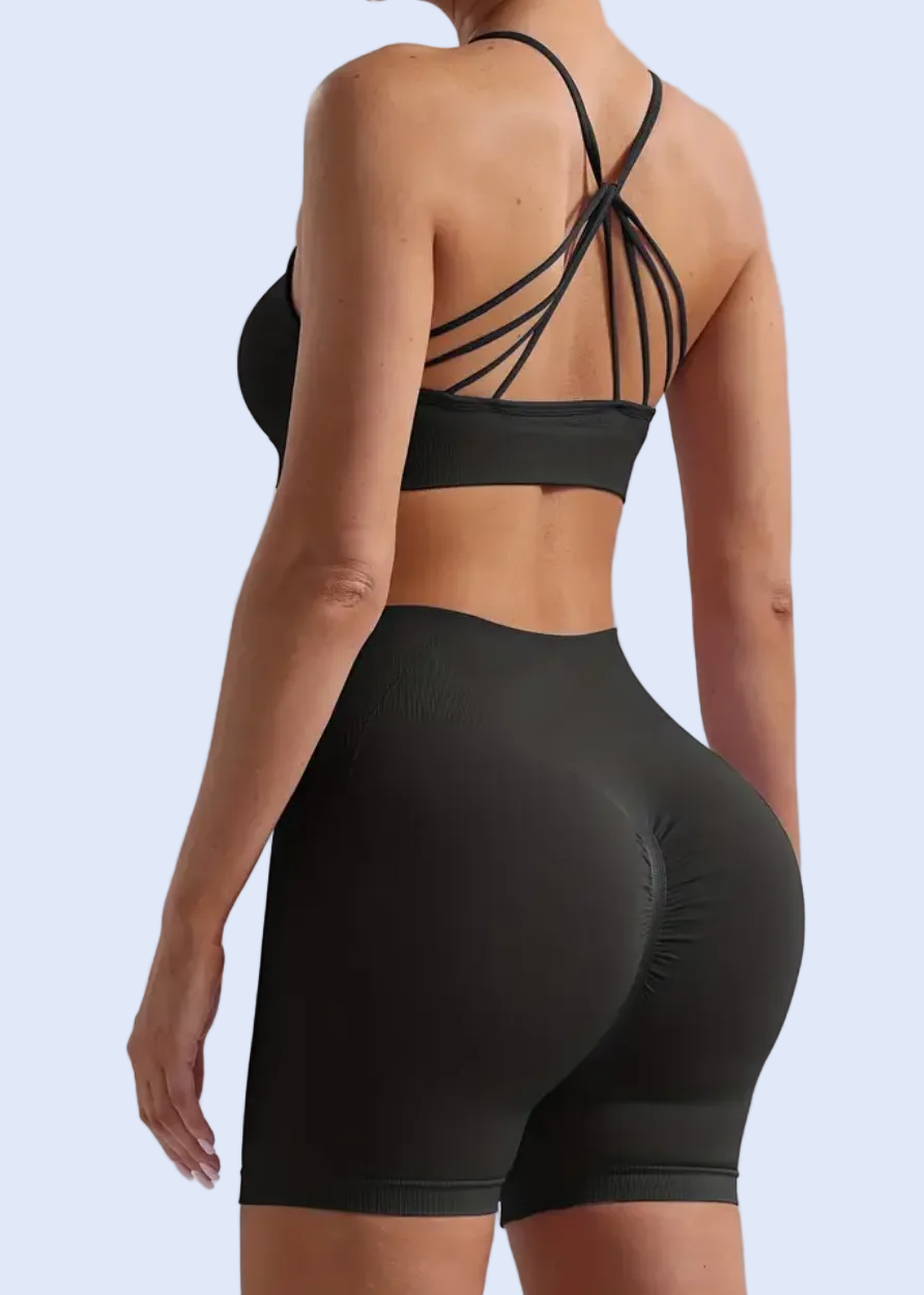 Person wearing a black sports bra and shorts set on a light gray background