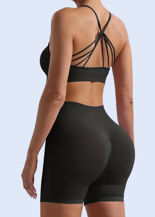 Person wearing a black sports bra and shorts set on a light gray background