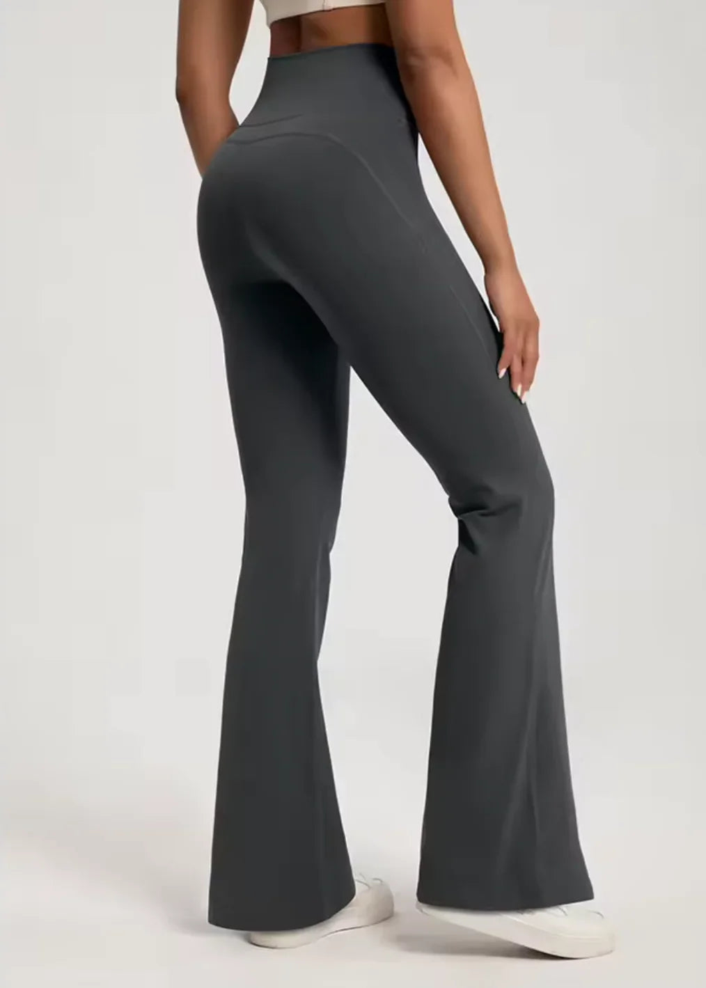 Woman wearing high-waisted black flared activewear leggings from GymDeity, side view