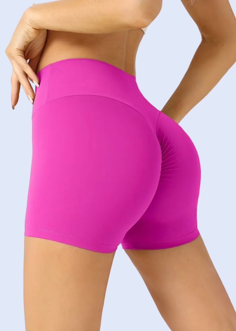 Person wearing bright pink high-waisted shorts on a plain background
