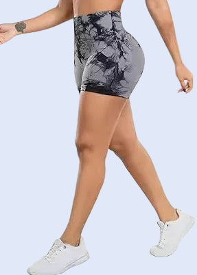 Woman wearing a white sports bra and gray patterned shorts on a white background