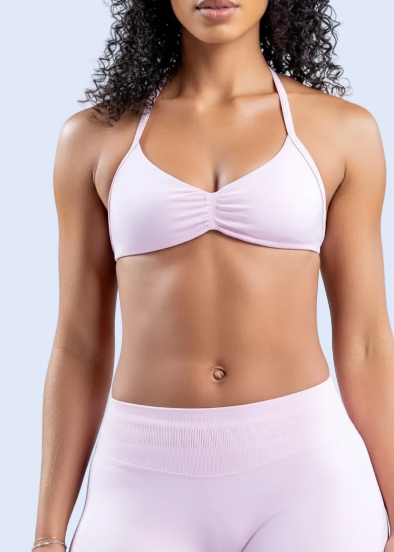Person wearing a pink sports bra and shorts on a light blue background