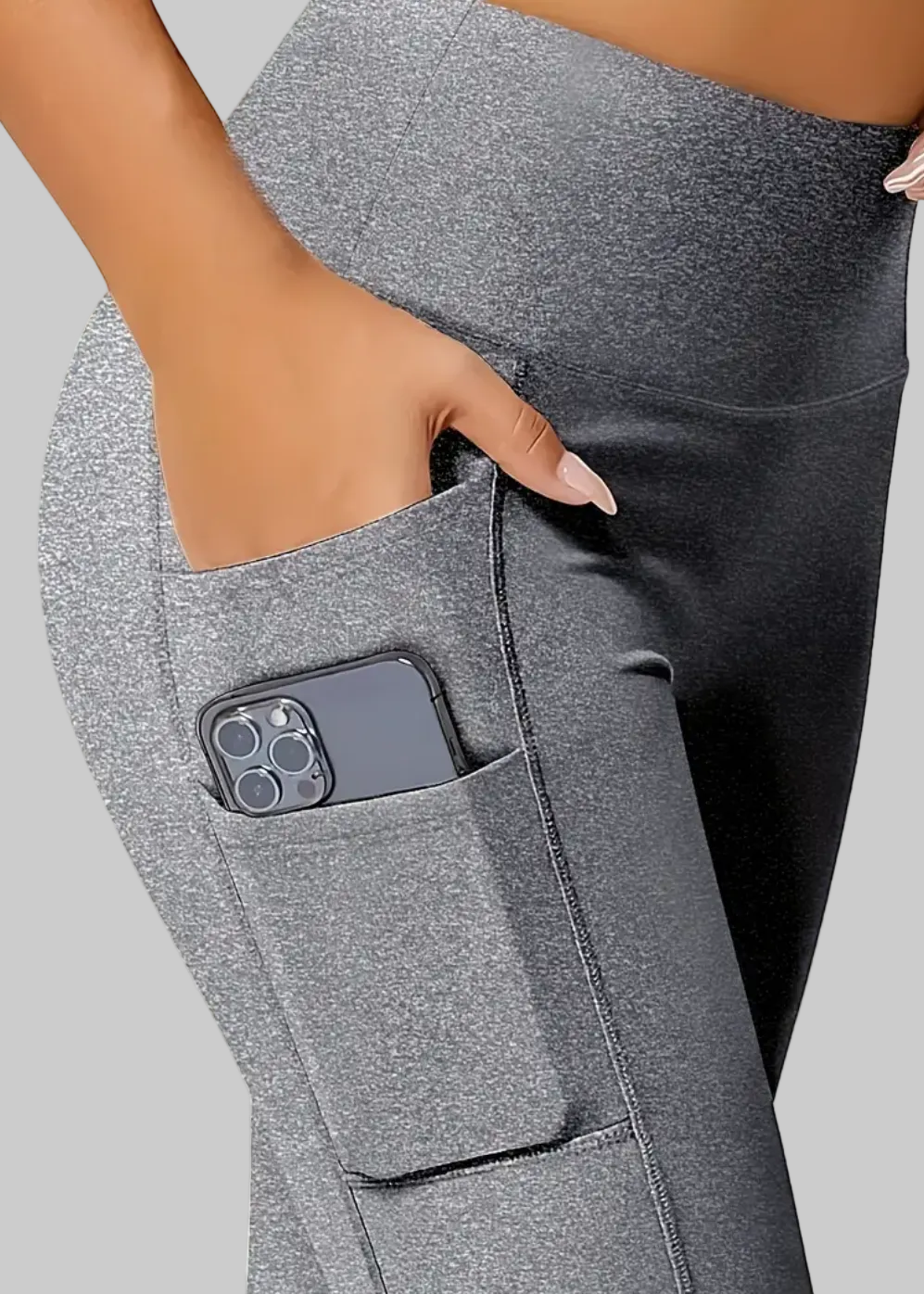 Gray leggings with a pocket holding a phone, on a neutral background