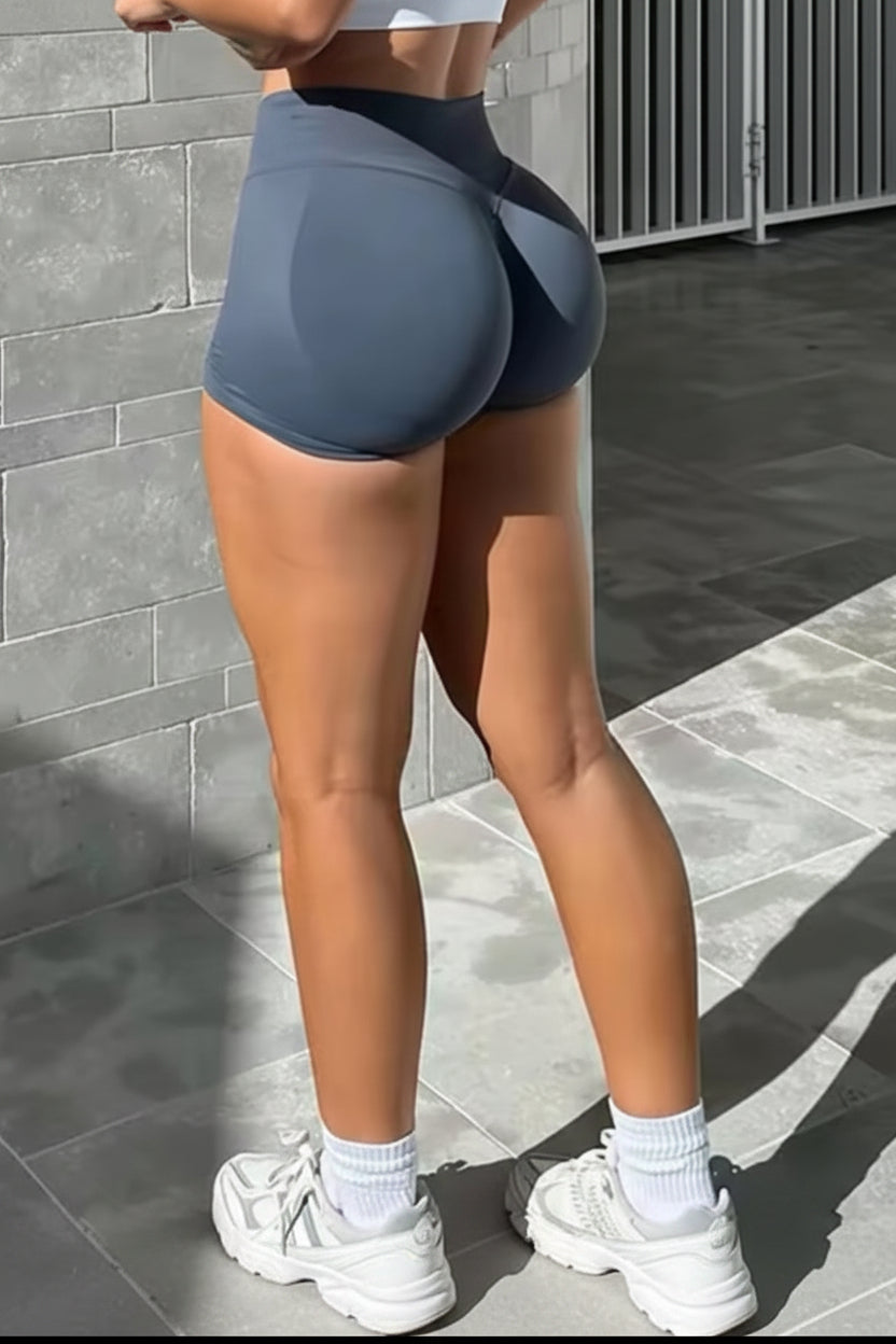 Person wearing gray high-waisted shorts standing against a gray tiled wall.