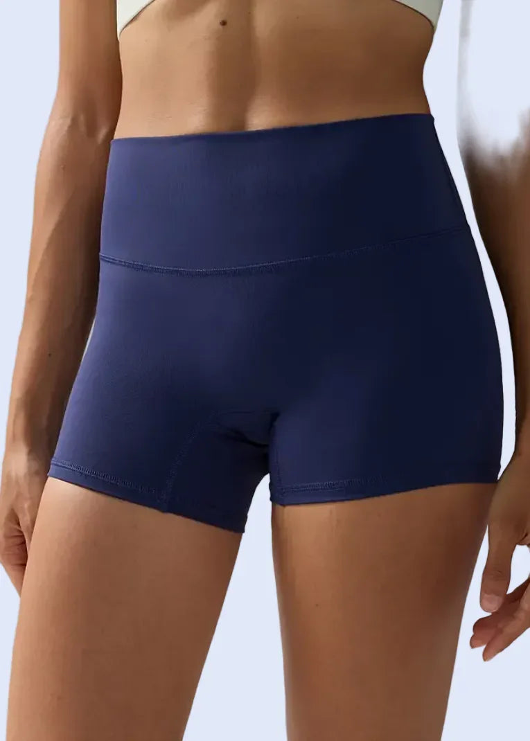 Navy blue athletic shorts worn by a person on a gray background