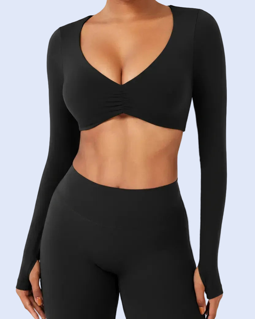 Person wearing a black long-sleeve sports bra and leggings on a light gray background