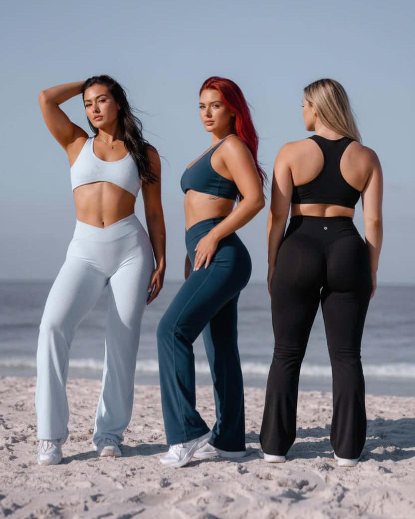 Three women in athletic wear standing on a beach.
