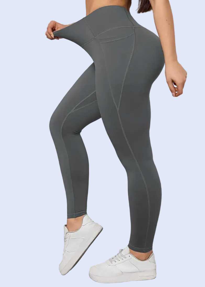 Person wearing gray leggings and white sneakers against a white wall.