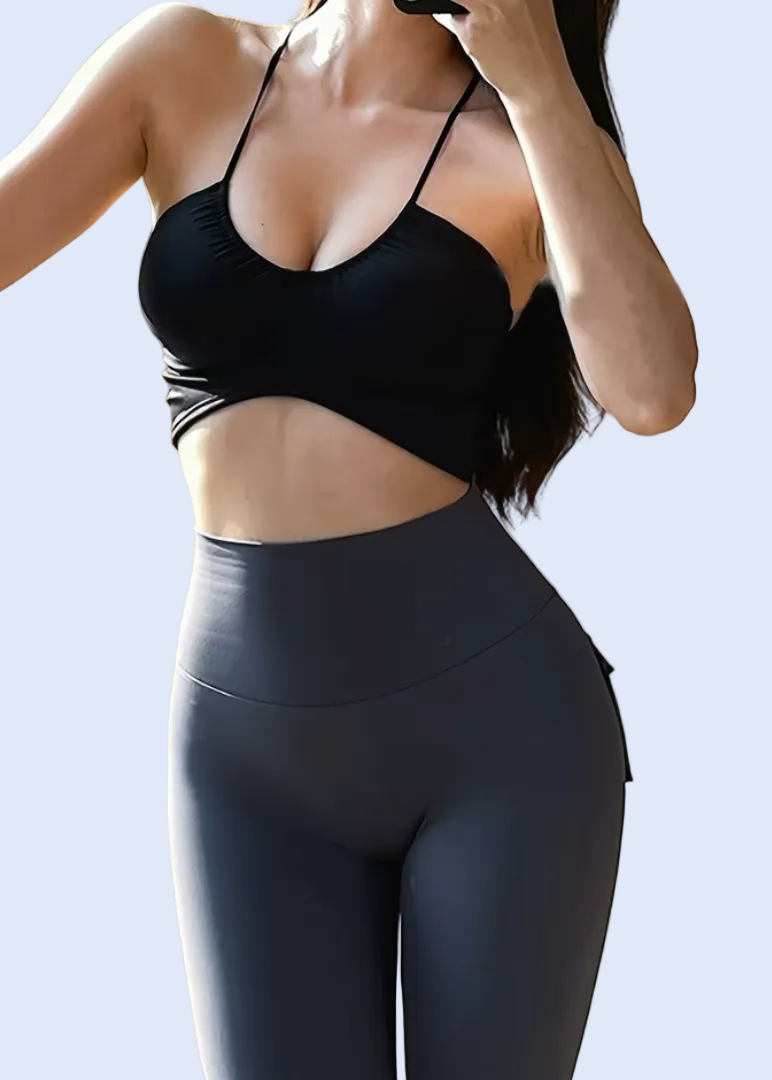 Person wearing a black sports bra and leggings in front of a mirror.
