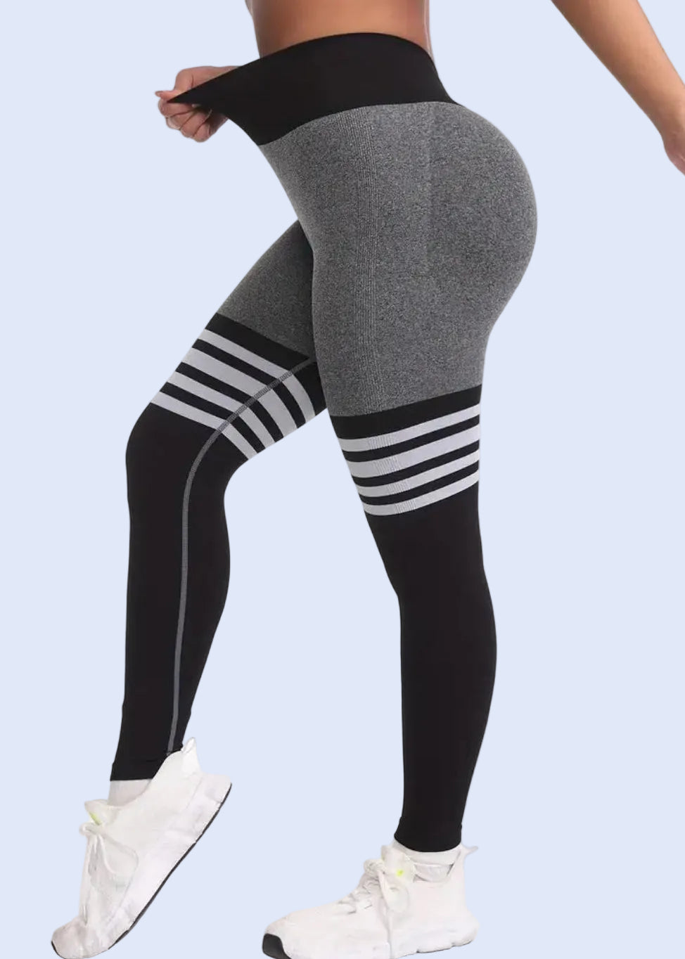 Gray leggings with black and white striped design worn by a person on a white background