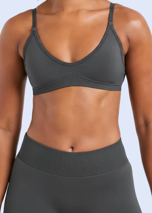 Person wearing a gray sports bra and leggings on a white background
