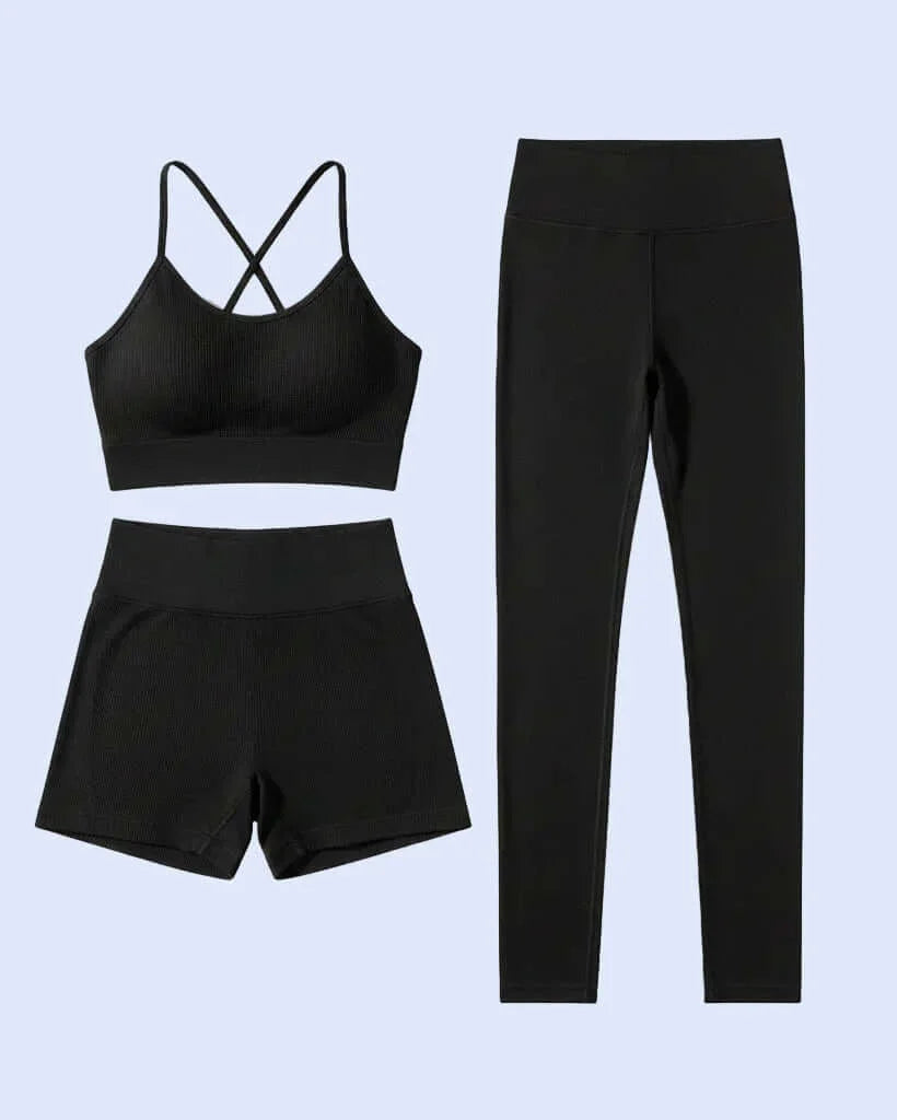 Woman in black athletic wear against a light wall 