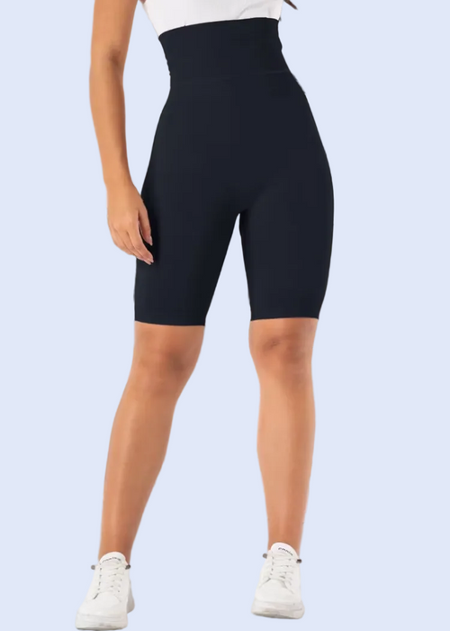 Person wearing black high-waisted bike shorts in a room with a window and plant.