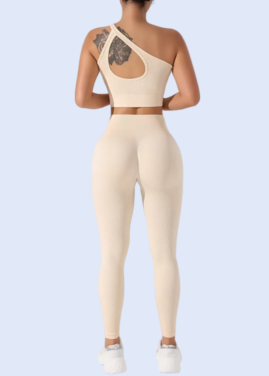 Person wearing a beige one-shoulder top and leggings on a white background