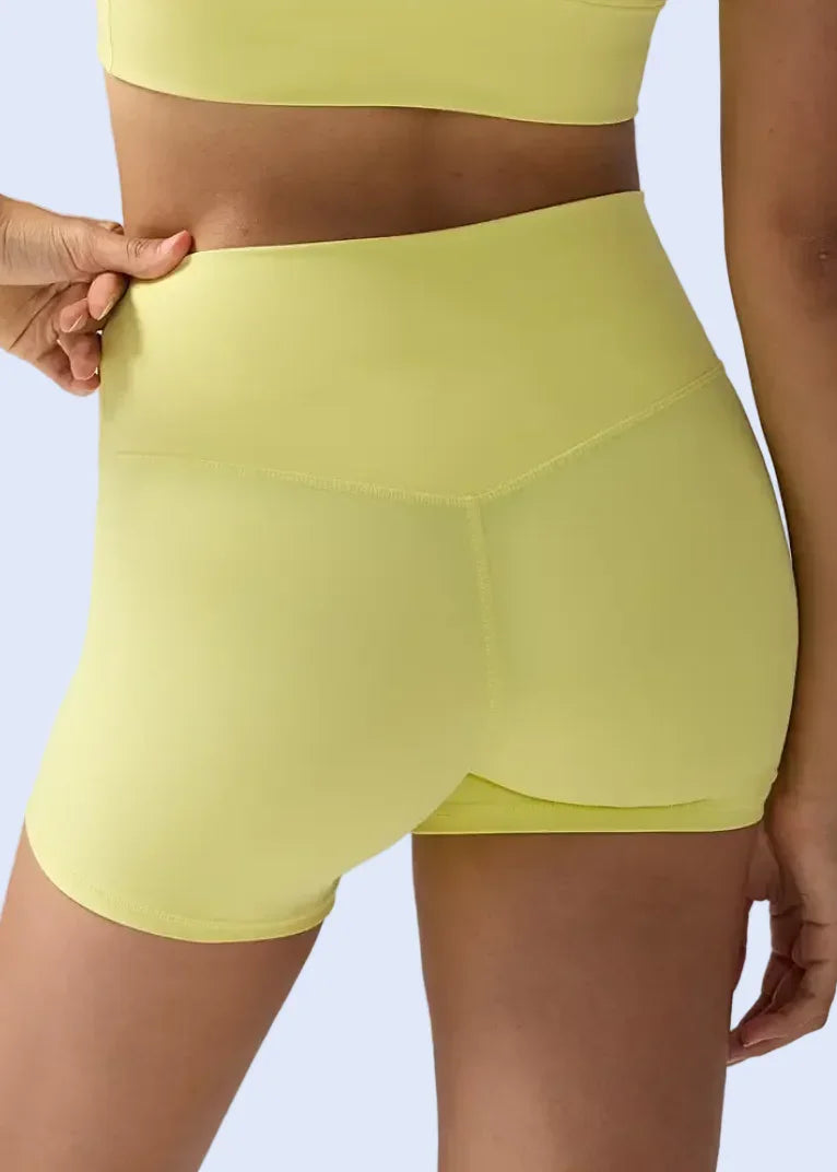 Person wearing bright yellow athletic shorts on a plain background