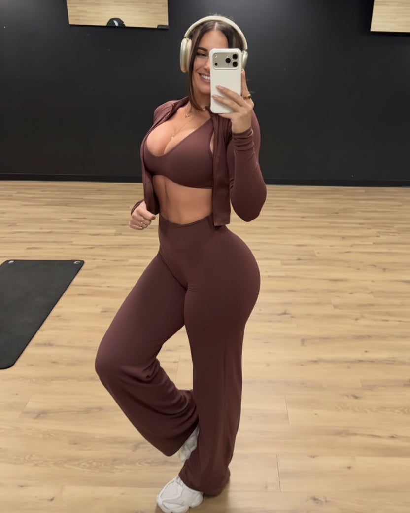 Person taking a mirror selfie in a gym wearing a brown athletic outfit.