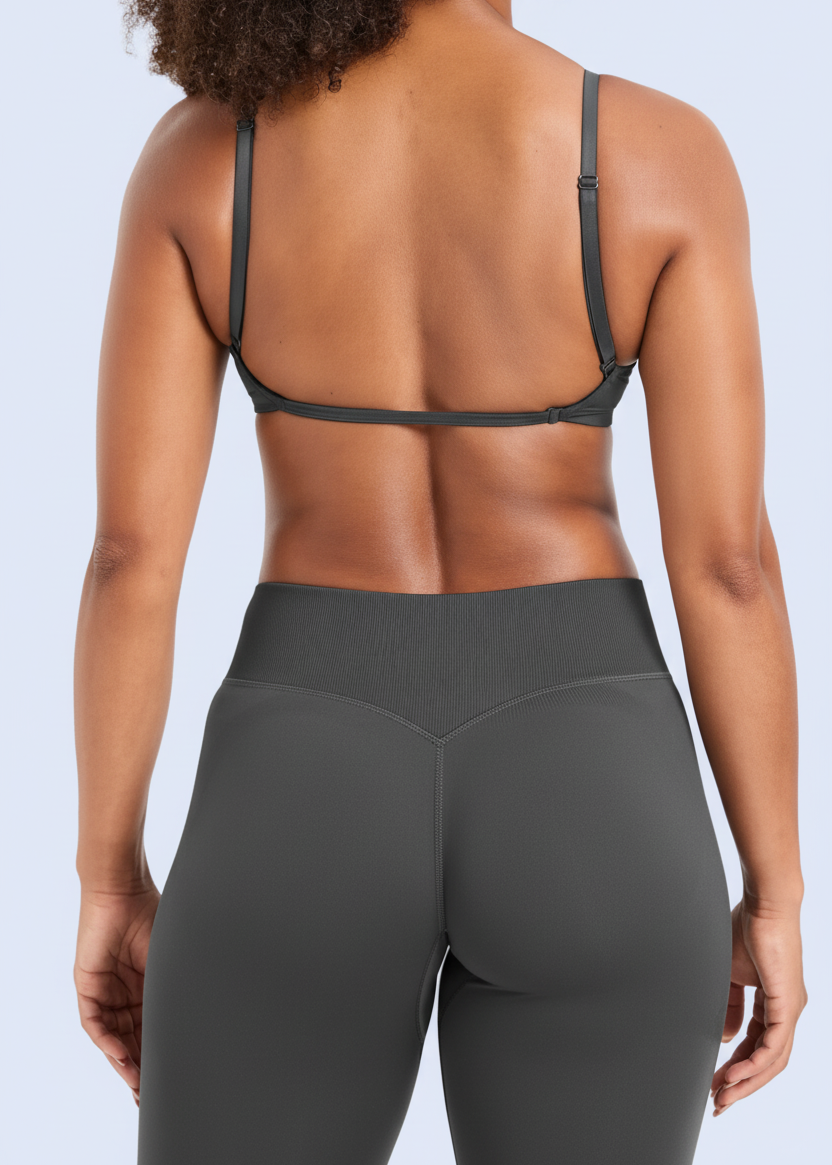 Person wearing a black sports bra and gray leggings on a white background