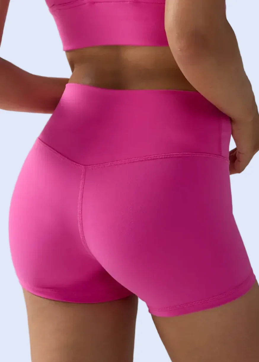 Person wearing bright pink athletic shorts on a plain background